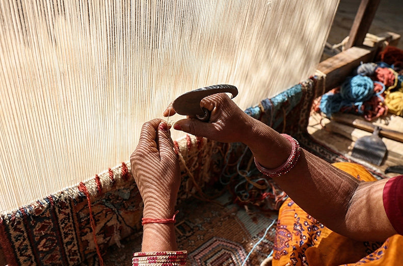 Artisan handknotting a rug on a loom